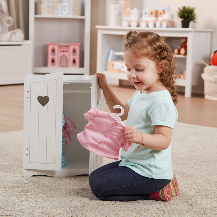 A kid playing with The Melissa & Doug Mine to Love Wooden Play Armoire Closet for Dolls, Stuffed Animals - White (17.3”H x 12.4”W x 8.5”D Assembled)