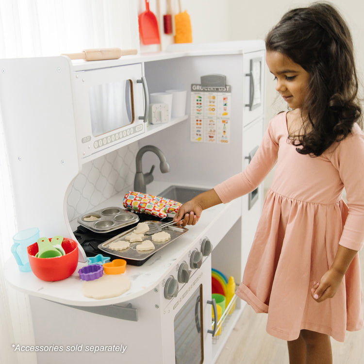 A kid playing with The Melissa & Doug Wooden Chef’s Pretend Play Toy Kitchen With “Ice” Cube Dispenser – Cloud White