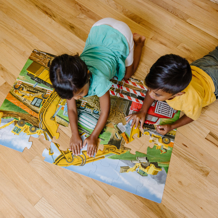 A kid playing with The Melissa & Doug Building Site Jumbo Jigsaw Floor Puzzle - 48 pcs