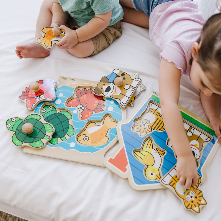 A kid playing with The Melissa & Doug Animals Jumbo Knob Wooden Puzzles Set - Fish and Pets