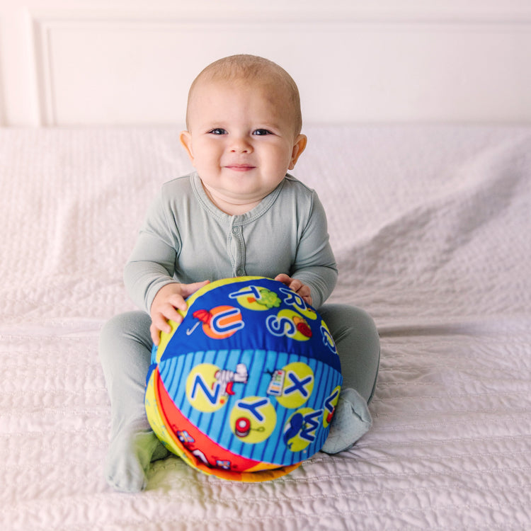 A kid playing with The Melissa & Doug K's Kids 2-in-1 Talking Ball Educational Toy - ABCs and Counting 1-10