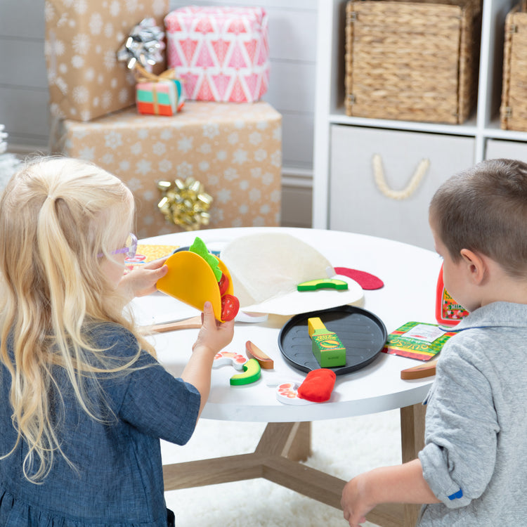 A kid playing with The Melissa & Doug Fill & Fold Taco & Tortilla Set, 43 Pieces – Sliceable Wooden Mexican Play Food, Skillet, and More