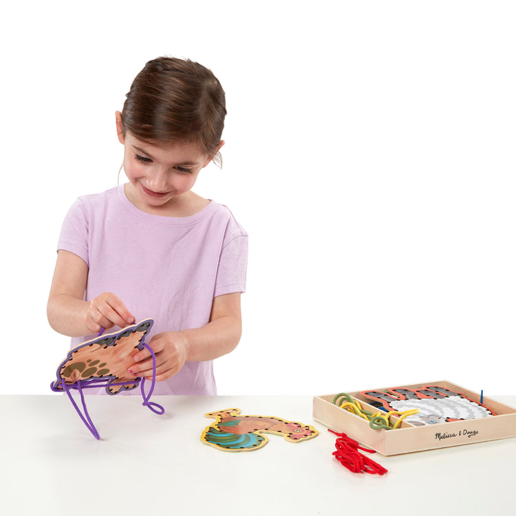 A child on white background with The Melissa & Doug Lace and Trace Activity Set: 5 Wooden Panels and 5 Matching Laces - Farm