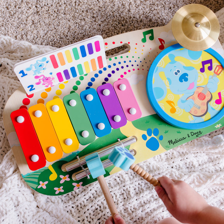 A kid playing with The Melissa & Doug Blue's Clues & You! Wooden Music Maker Board (5 Instruments)