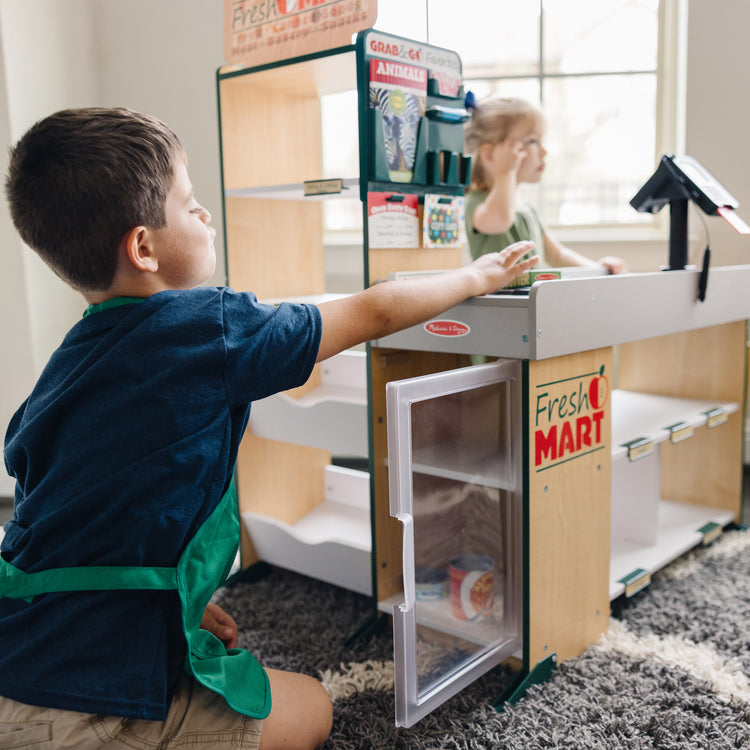 A kid playing with The Melissa & Doug Freestanding Wooden Fresh Mart Grocery Store