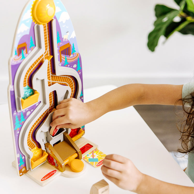 A kid playing with The Melissa & Doug Fun at the Fair! Wooden Ring the Bell Game