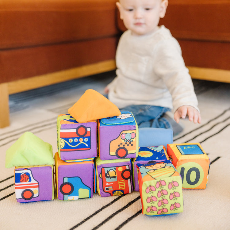 A kid playing with The Melissa & Doug K's Kids Match and Build Soft Blocks Set