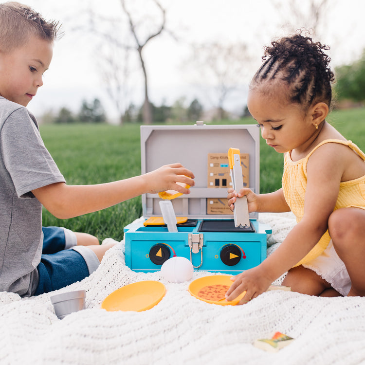 A kid playing with The Melissa & Doug Let’s Explore Camp Stove Play Set – 24 Pieces