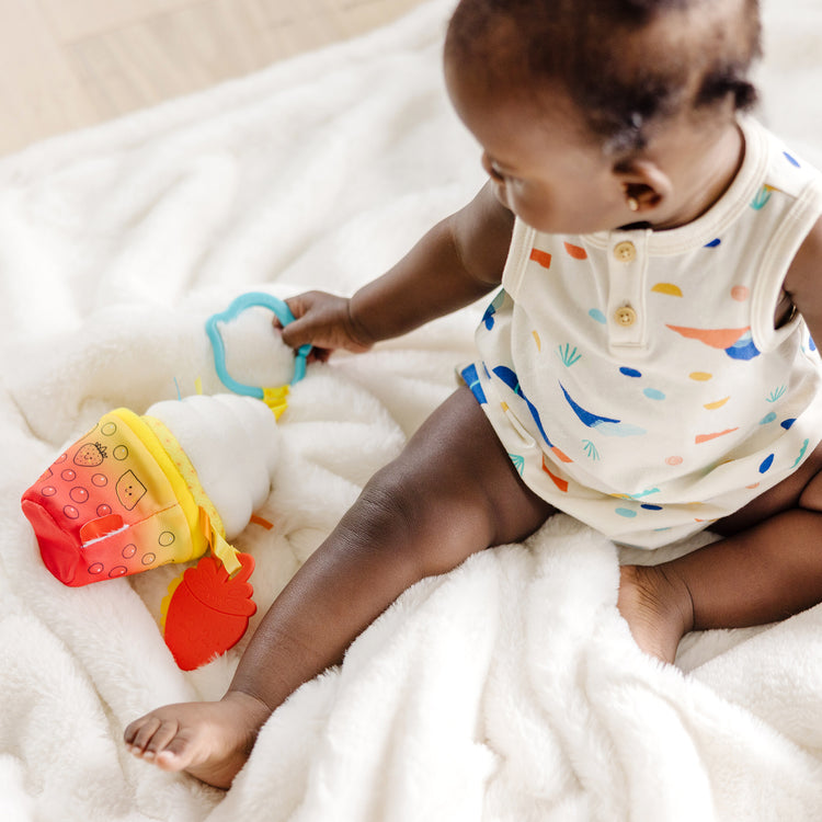 A kid playing with The Melissa & Doug Multi-Sensory Bubble Tea Take-Along Clip-On Infant Toy