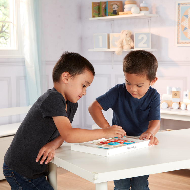 A kid playing with The Melissa & Doug Wooden Tic-Tac-Toe Board Game with 10 Self-Storing Wooden Game Pieces (12.5” W x 8.5” L x 1.25” D)