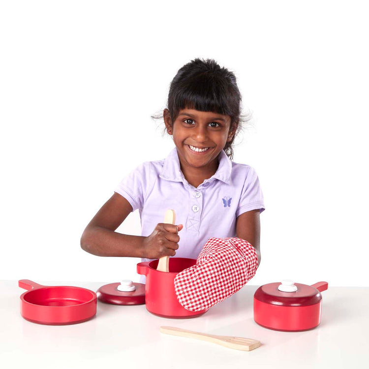 A child on white background with The Melissa & Doug Deluxe Wooden Kitchen Accessory Play Set - Pots & Pans (8 pcs)