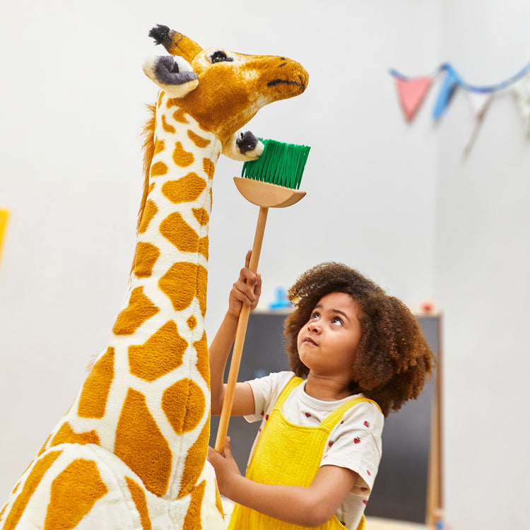 A kid playing with The Melissa & Doug Giant Giraffe - Lifelike Plush Stuffed Animal (over 4 feet tall)