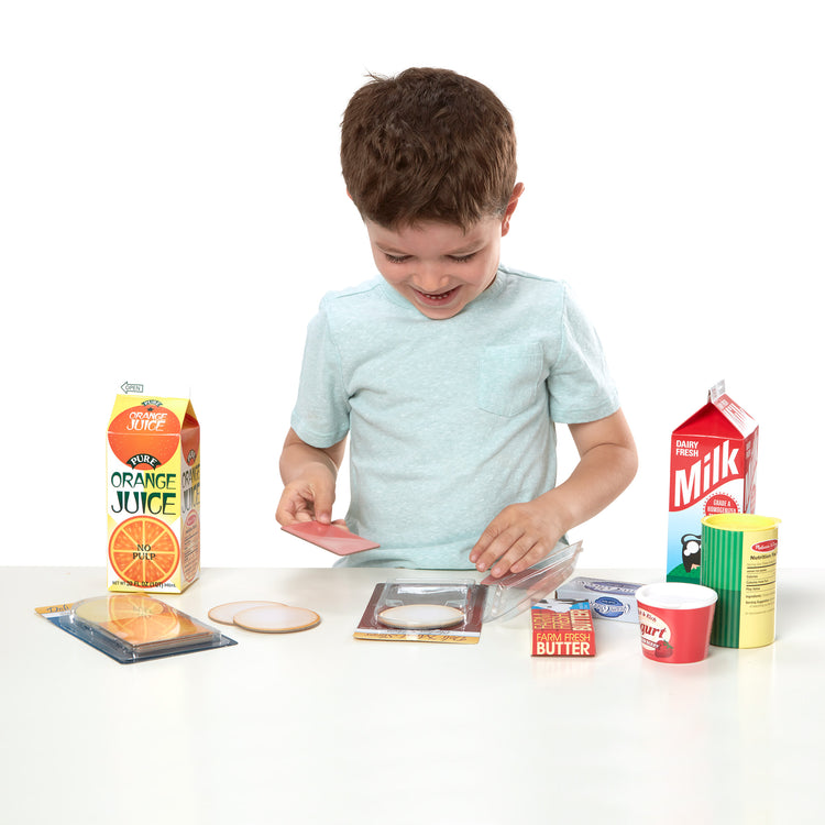 A child on white background with The Melissa & Doug Fridge Groceries Play Food Cartons (8 pieces)