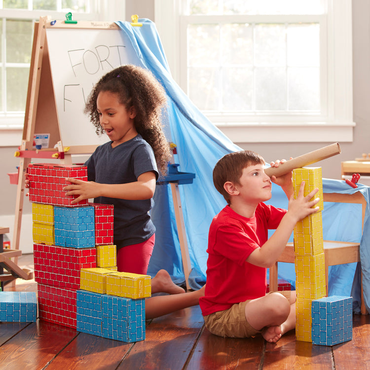 A kid playing with The Melissa & Doug Jumbo Extra-Thick Cardboard Building Blocks - 40 Blocks in 3 Sizes