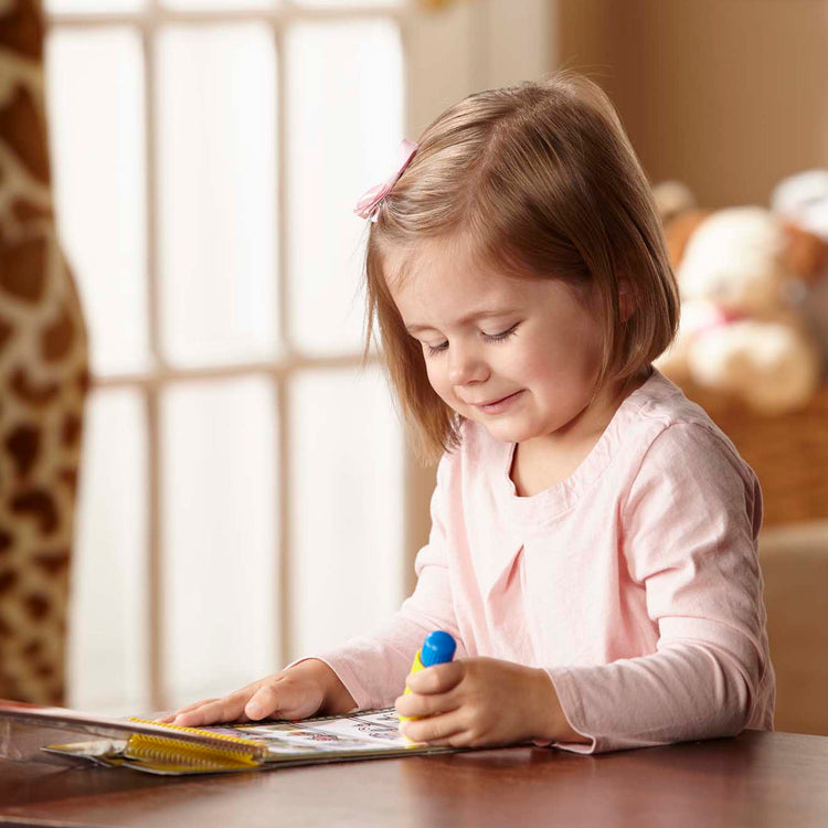 A kid playing with The Melissa & Doug On the Go Water Wow! Reusable Water-Reveal Activity Pad - Vehicles