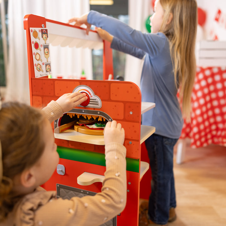 A kid playing with The Melissa & Doug Wooden Pizza Food Truck Activity Center with Play Food, for Boys and Girls 3+