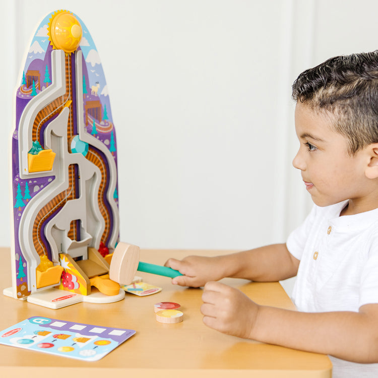 A kid playing with The Melissa & Doug Fun at the Fair! Wooden Ring the Bell Game