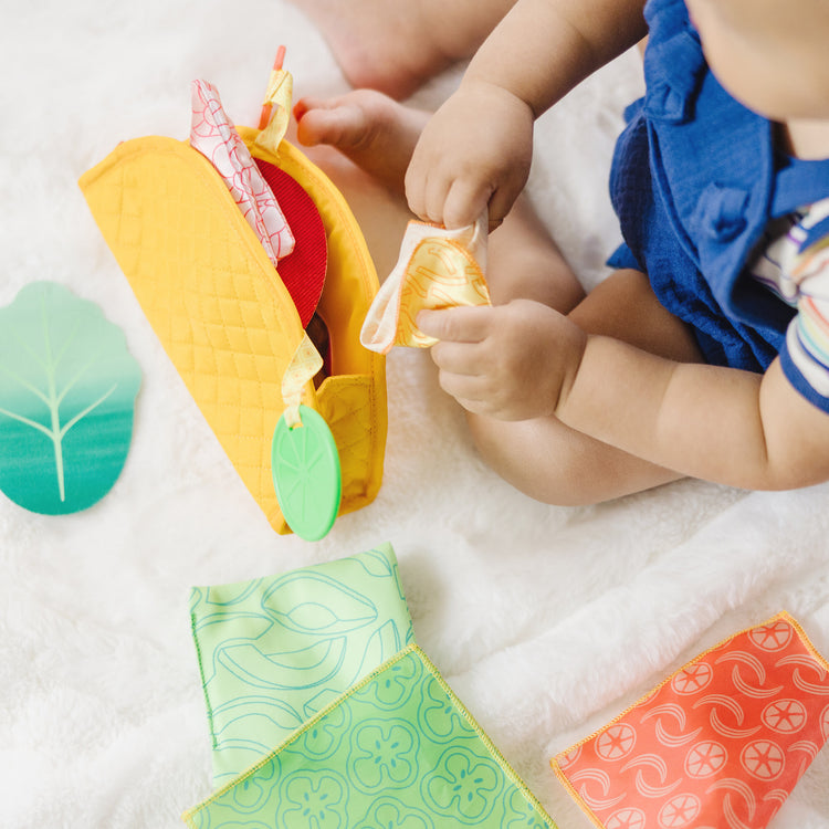 A kid playing with The Melissa & Doug Multi-Sensory Soft Taco Fill & Spill Infant Toy