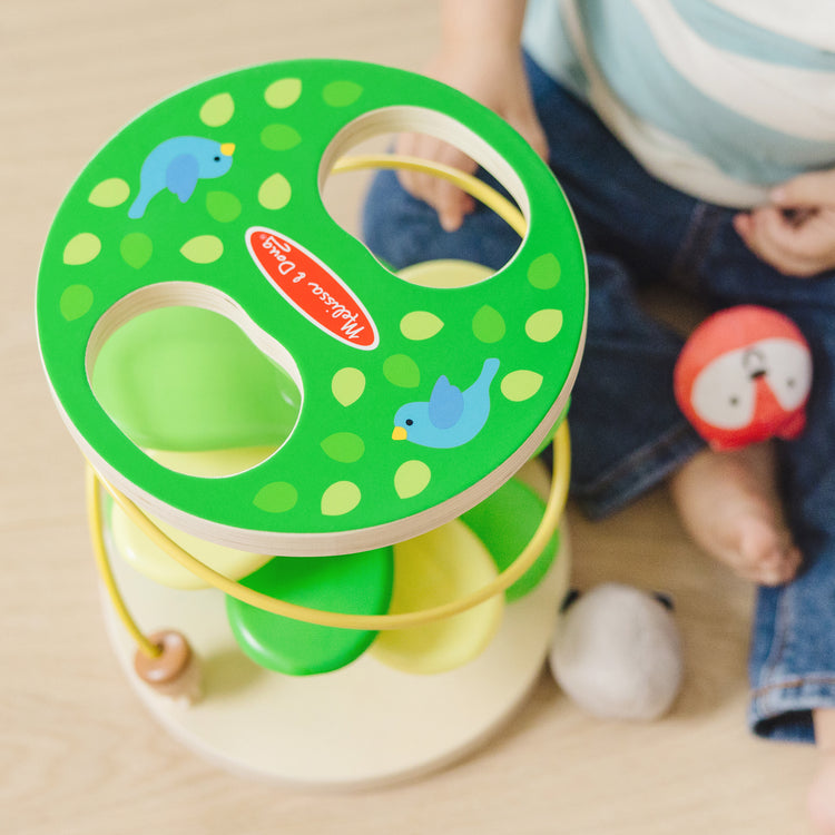 A kid playing with The Melissa & Doug Rollables Treehouse Twirl Infant and Toddler Toy (3 Pieces)