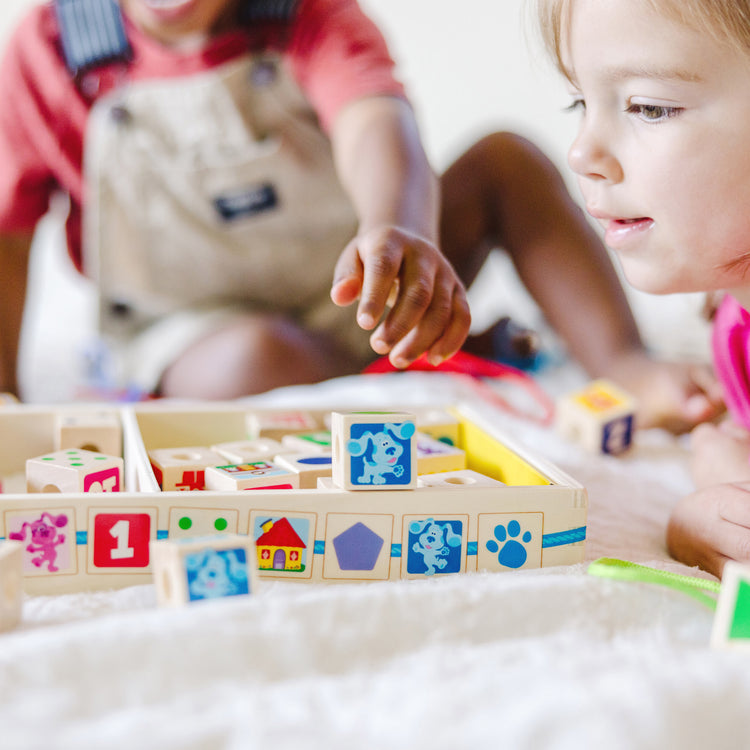 A kid playing with The Melissa & Doug Blue’s Clues & You! Wooden Lacing Beads - 25 Beads, 4 Cords