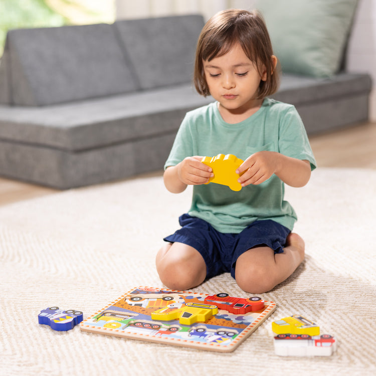 A kid playing with The Melissa & Doug Construction Vehicles Wooden Chunky Puzzle (6 pcs)