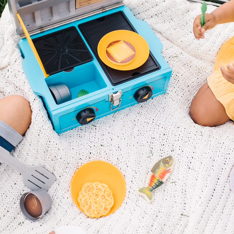 A kid playing with The Melissa & Doug Let’s Explore Camp Stove Play Set – 24 Pieces