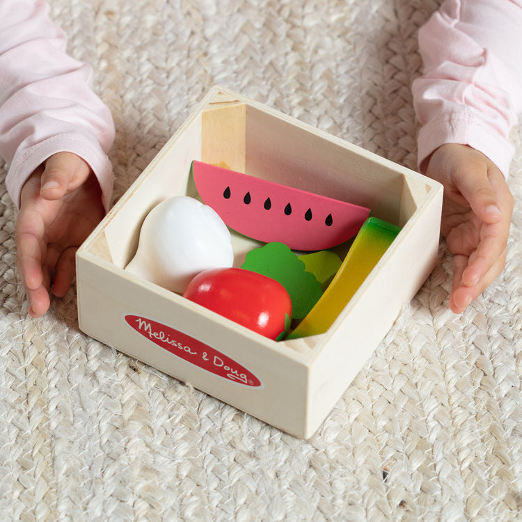 A kid playing with The Melissa & Doug Wooden Food Groups Play Food Set – Produce