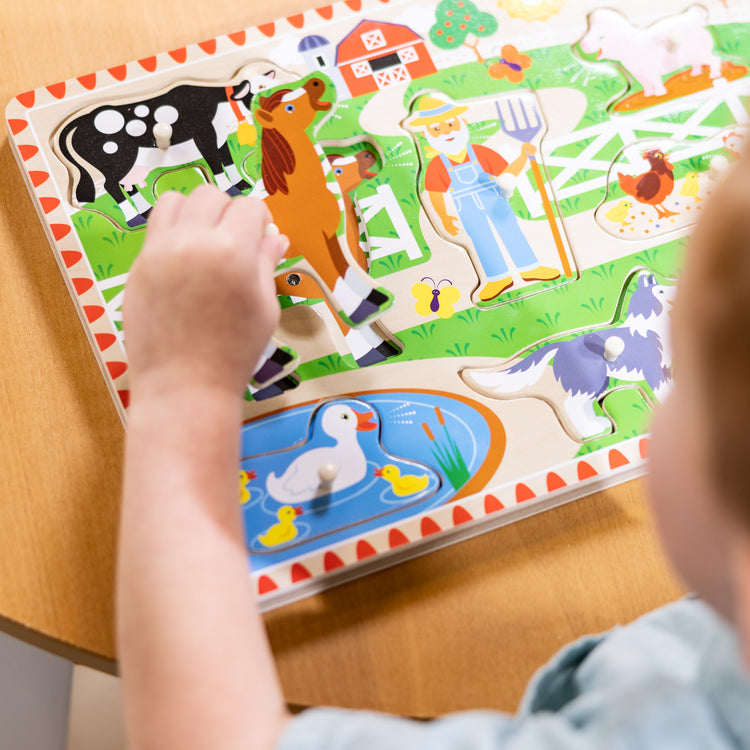 A kid playing with The Melissa & Doug Old MacDonald's Farm Sound Puzzle