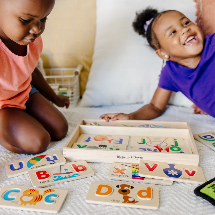 A kid playing with The Melissa & Doug ABC Picture Boards - Educational Toy With 13 Double-Sided Wooden Boards and 52 Letters