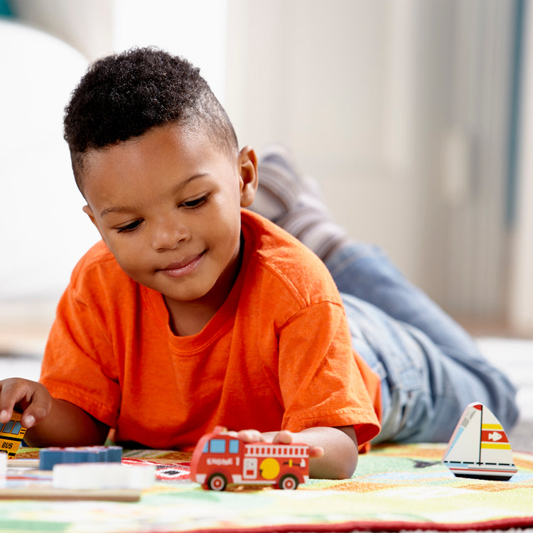 A kid playing with The Melissa & Doug Vehicles Wooden Chunky Puzzle - Plane, Train, Cars, and Boats (9 pcs)