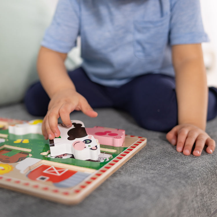 A kid playing with The Melissa & Doug Farm Wooden Chunky Puzzle (8 pcs)