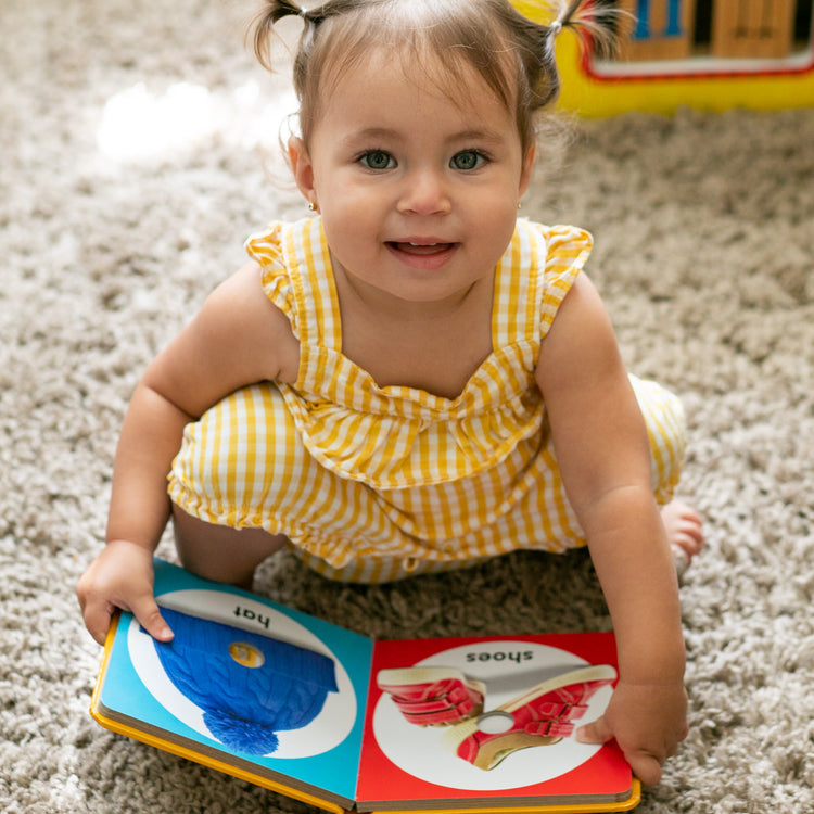 A kid playing with The Melissa & Doug Children’s Book – Poke-a-Dot: First Colors (Board Book with Buttons to Pop)