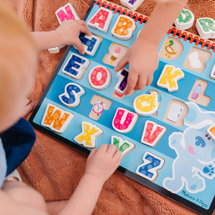 A kid playing with The Melissa & Doug Blue's Clues & You! Wooden Chunky Puzzle - Alphabet (26 Pieces)