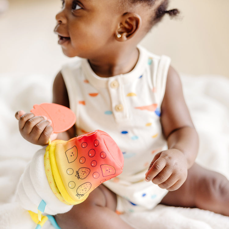 A kid playing with The Melissa & Doug Multi-Sensory Bubble Tea Take-Along Clip-On Infant Toy