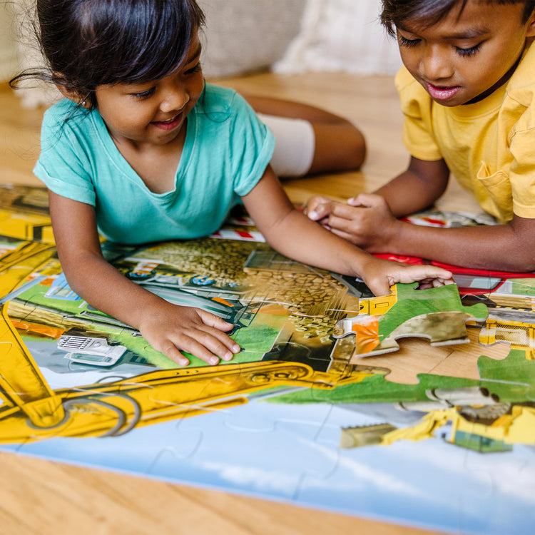 A kid playing with The Melissa & Doug Building Site Jumbo Jigsaw Floor Puzzle - 48 pcs