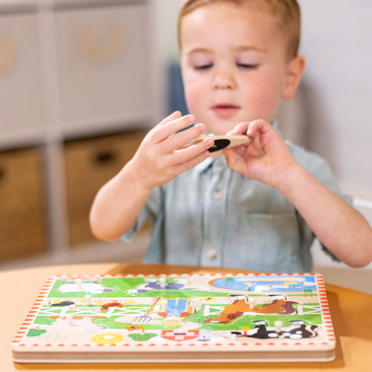 A kid playing with The Melissa & Doug Old MacDonald's Farm Sound Puzzle