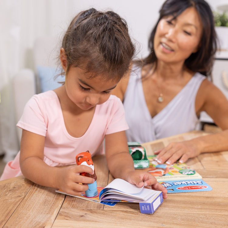 A kid playing with The Melissa & Doug Sticker WOW!™ Fox Bundle: 24-Page Activity Pad, Sticker Stamper, 500 Stickers, Arts and Crafts Fidget Toy Collectible Character