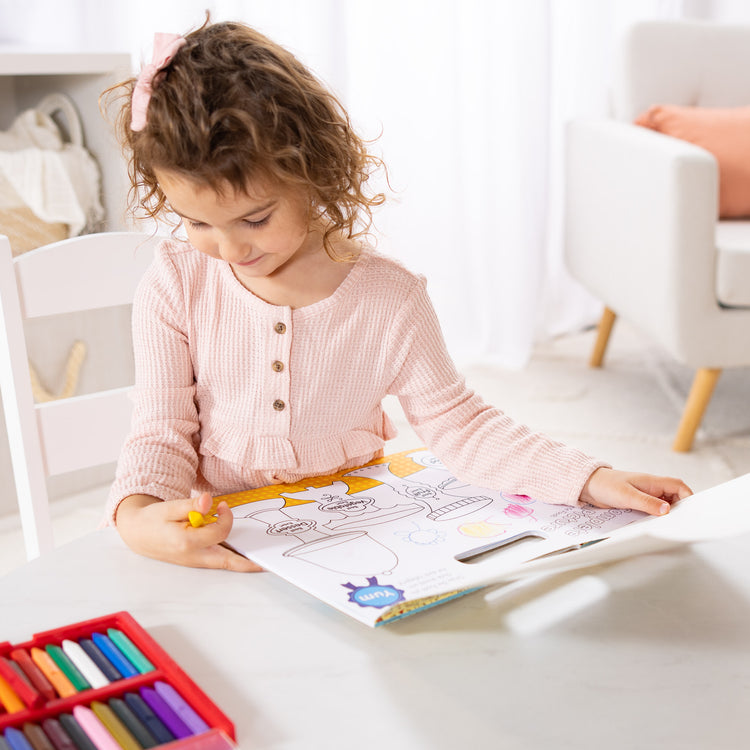 A kid playing with The Melissa & Doug Playmats Food Fun Take-Along Paper Coloring And Learning Activity Pads (24 Pages)