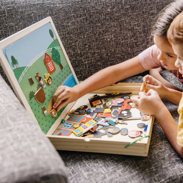 A kid playing with The Melissa & Doug Wooden Magnetic Matching Picture Game With 119 Magnets and Scene Cards