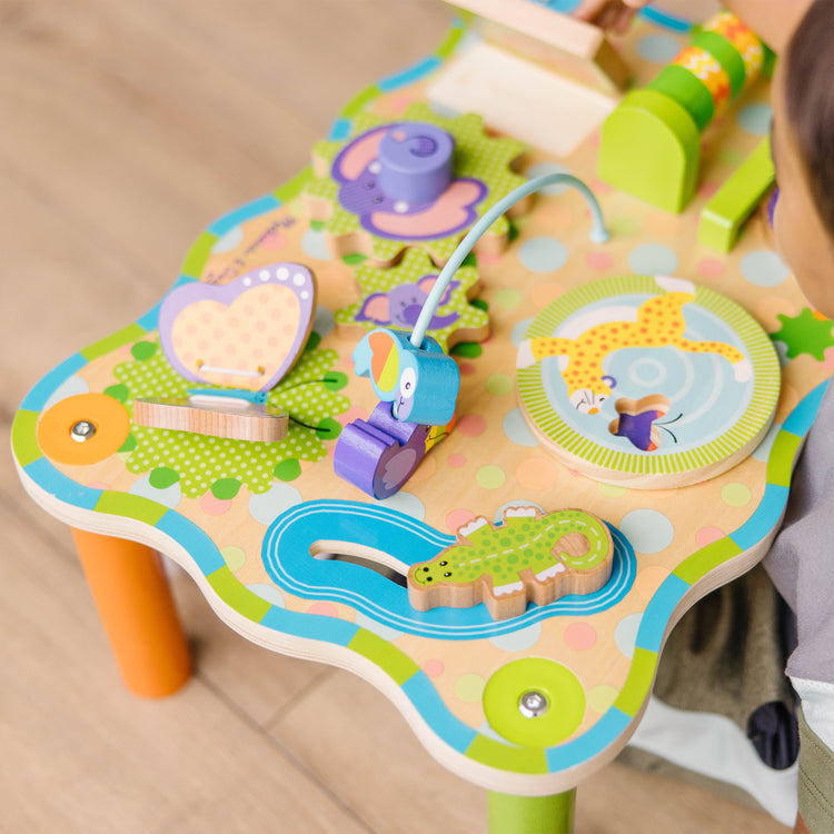 A kid playing with The Melissa & Doug First Play Children’s Jungle Wooden Activity Table for Toddlers