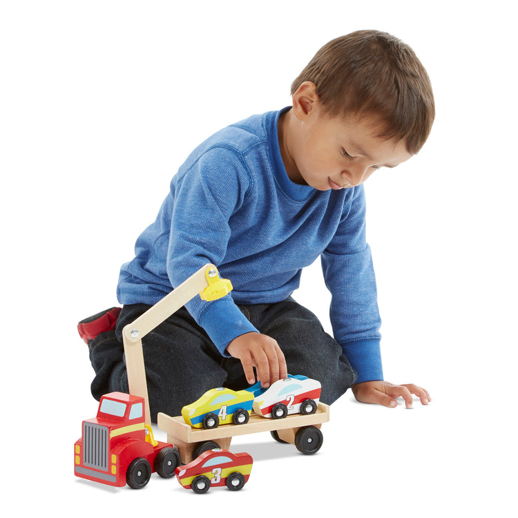 A child on white background with The Melissa & Doug Magnetic Car Loader Wooden Toy Set With 4 Cars and 1 Semi-Trailer Truck