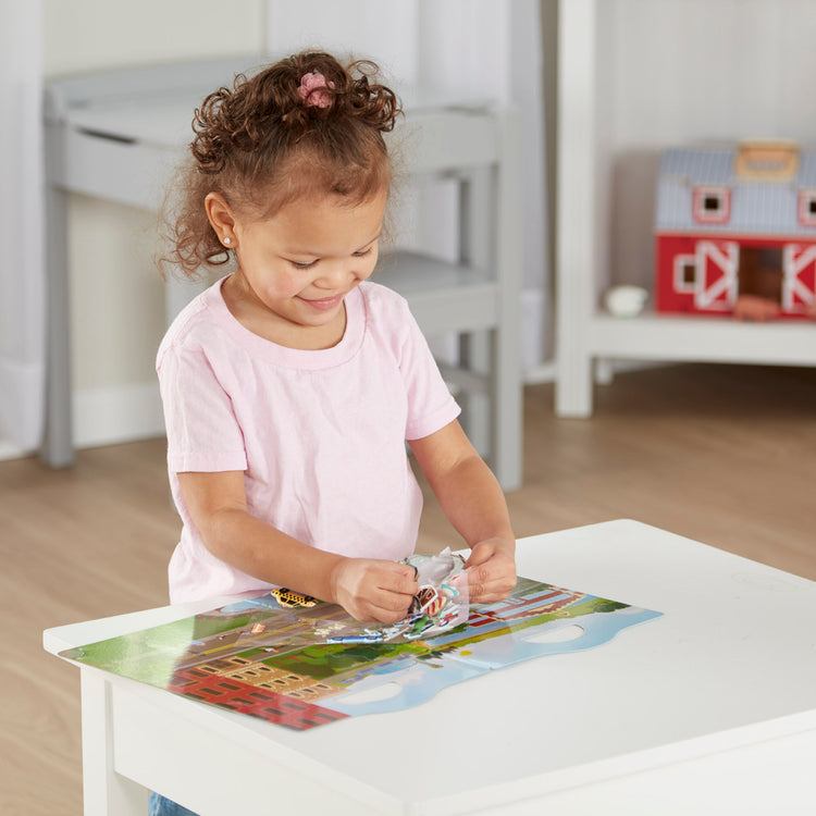 A kid playing with The Melissa & Doug Vehicles Puffy Sticker Play Set Travel Toy with Double-Sided Background, 32 Reusable Puffy Stickers