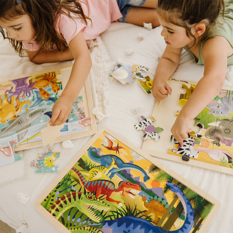 A kid playing with The Melissa & Doug Jigsaw Puzzle Bundle (Dinosaur,Safari and Ocean)