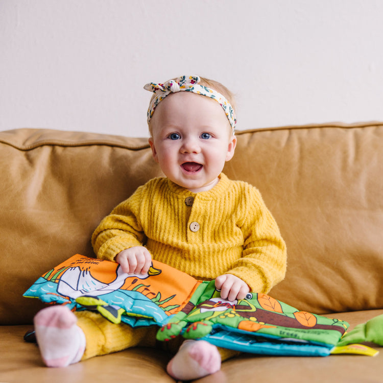 A kid playing with The Melissa & Doug Soft Activity Baby Book - Whose Feet?