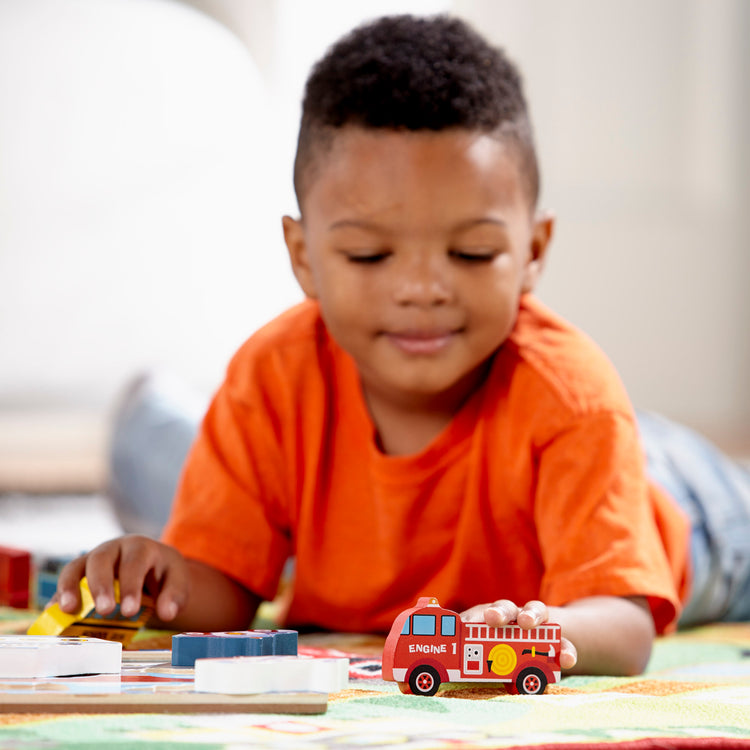 A kid playing with The Melissa & Doug Vehicles Wooden Chunky Puzzle - Plane, Train, Cars, and Boats (9 pcs)