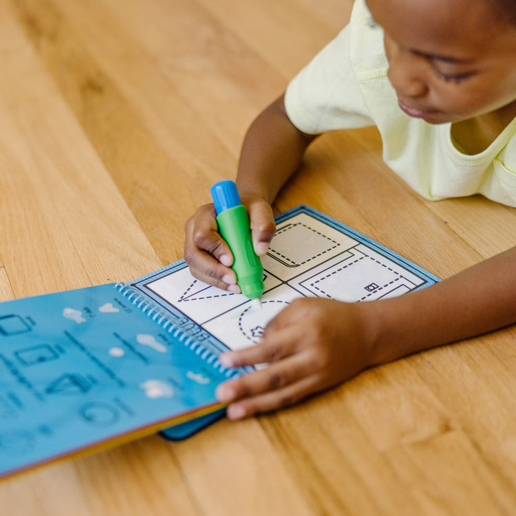 A kid playing with The Melissa & Doug On the Go Water Wow! Reusable Water-Reveal Activity Pad - Colors, Shapes