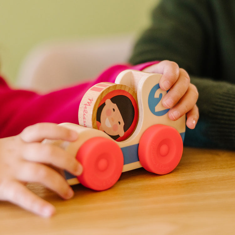 A kid playing with The Melissa & Doug GO Tots Wooden Race Cars (2 Cars, 2 Disks)