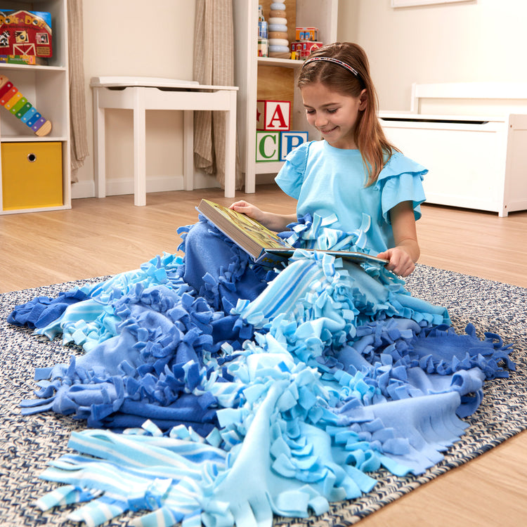 A kid playing with The Melissa & Doug Created by Me! Striped Fleece Quilt No-Sew Craft Kit (48 squares, 4 feet x 5 feet)