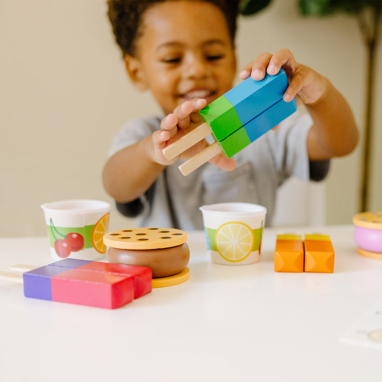 A kid playing with The Melissa & Doug Wooden Frozen Treats Ice Cream Play Set (24 pcs) - Play Food and Accessories