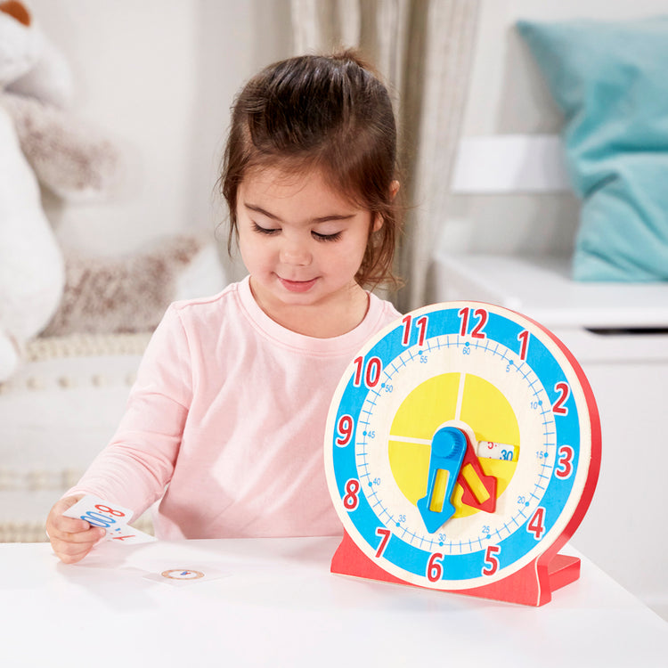 A kid playing with The Melissa & Doug Turn & Tell Wooden Clock - Educational Toy With 12+ Reversible Time Cards